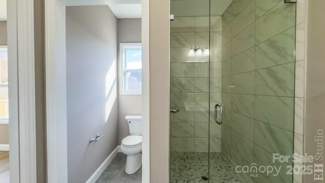 bathroom featuring a shower with door and toilet