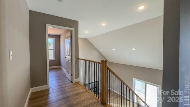 corridor with vaulted ceiling and hardwood / wood-style floors