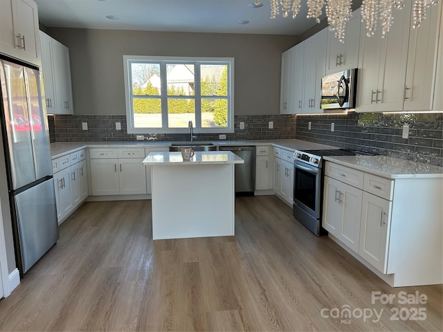 kitchen with sink, stainless steel appliances, white cabinets, a kitchen island, and decorative backsplash