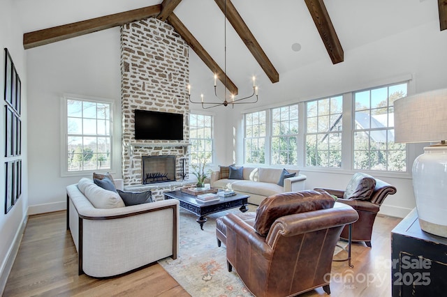 living room with high vaulted ceiling, a large fireplace, a chandelier, beam ceiling, and light hardwood / wood-style flooring