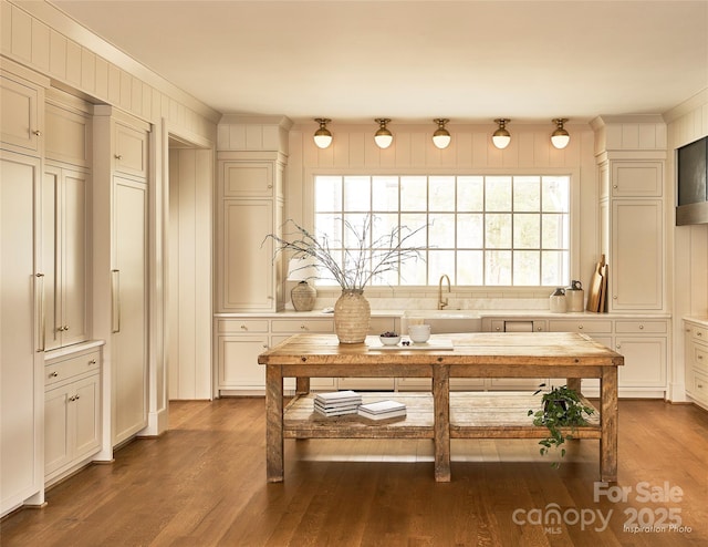 kitchen featuring a sink, crown molding, light countertops, and wood finished floors