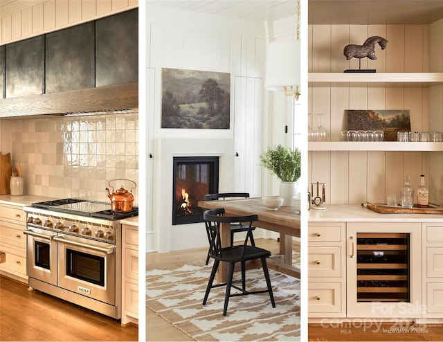 kitchen with wall chimney exhaust hood, light countertops, beverage cooler, double oven range, and tasteful backsplash