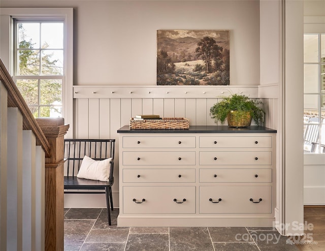 interior space with stairs, a wainscoted wall, and stone tile flooring