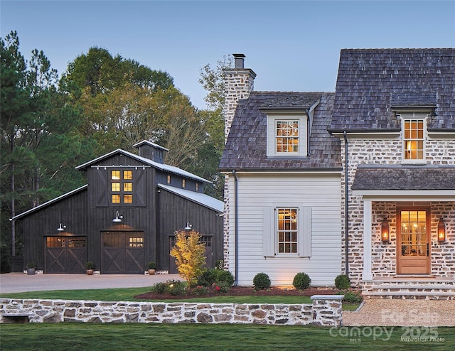 back of property with a lawn, a chimney, and a garage