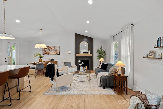 living room with vaulted ceiling, light hardwood / wood-style floors, and a healthy amount of sunlight