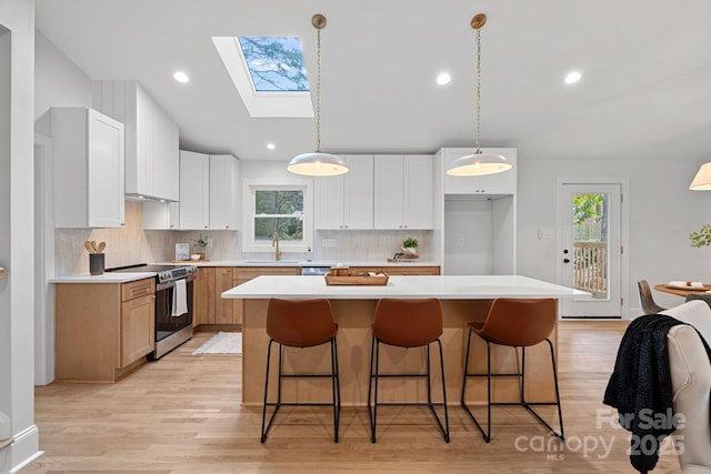 kitchen featuring sink, pendant lighting, white cabinetry, a kitchen island, and electric stove