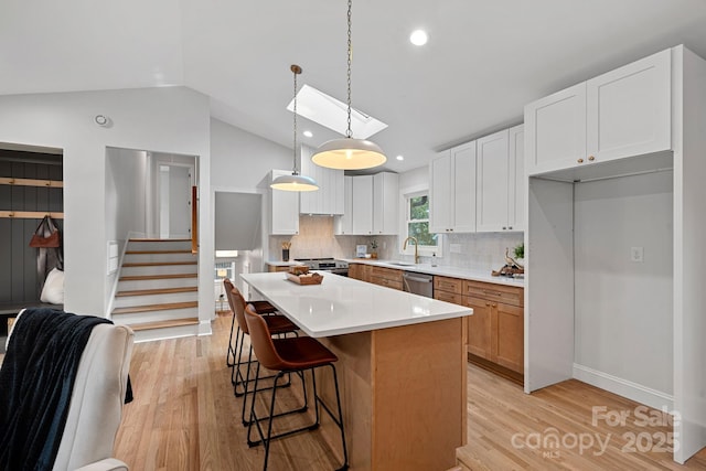 kitchen featuring sink, white cabinetry, decorative light fixtures, a center island, and appliances with stainless steel finishes