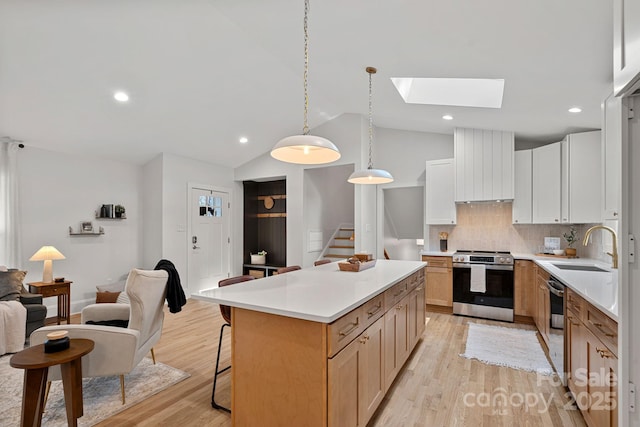 kitchen with sink, white cabinetry, a kitchen island, stainless steel appliances, and wall chimney range hood