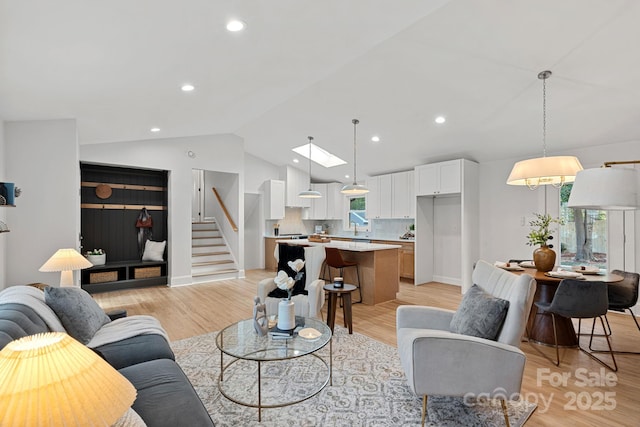 living room with lofted ceiling with skylight and light hardwood / wood-style floors