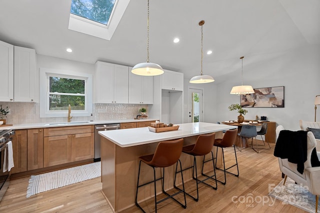 kitchen with sink, white cabinetry, a center island, appliances with stainless steel finishes, and pendant lighting