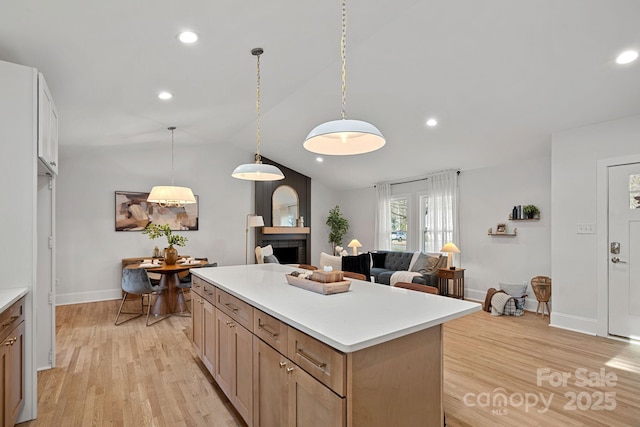 kitchen with vaulted ceiling, a kitchen island, pendant lighting, and light hardwood / wood-style floors