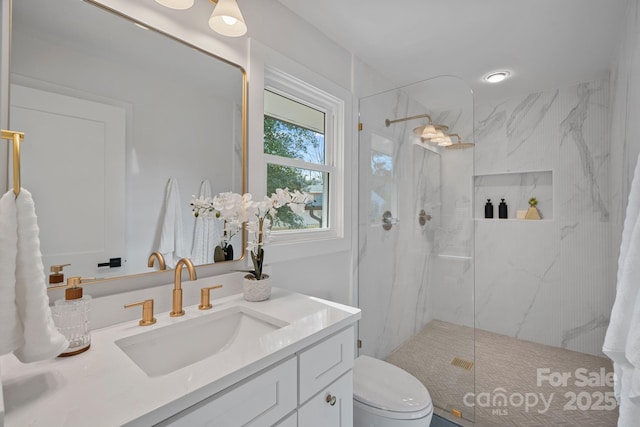 bathroom with tiled shower, vanity, and toilet