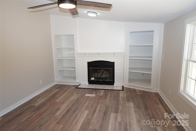 unfurnished living room with ceiling fan, built in features, and dark hardwood / wood-style flooring