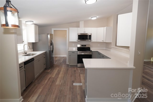 kitchen with pendant lighting, sink, gray cabinets, appliances with stainless steel finishes, and vaulted ceiling