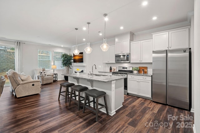 kitchen with appliances with stainless steel finishes, white cabinetry, and a center island with sink