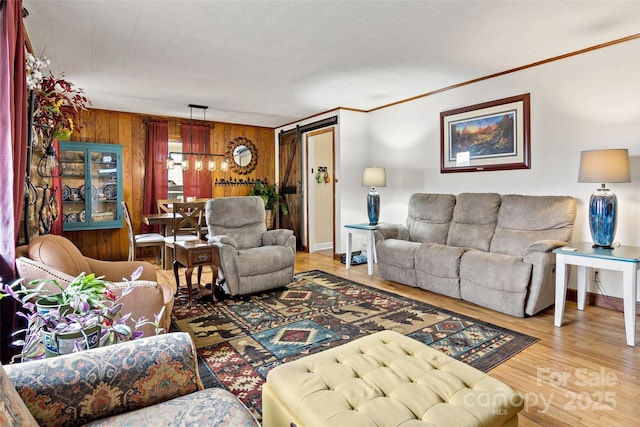 living room featuring hardwood / wood-style floors, crown molding, a barn door, and wood walls