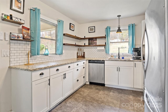 kitchen with white cabinetry, appliances with stainless steel finishes, sink, and decorative light fixtures