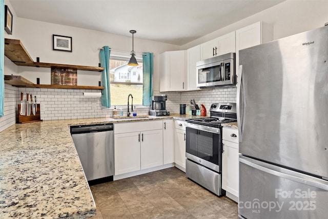 kitchen featuring sink, white cabinetry, backsplash, stainless steel appliances, and decorative light fixtures