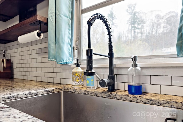 room details featuring tasteful backsplash, sink, and light stone counters