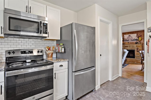 kitchen featuring appliances with stainless steel finishes, stone countertops, decorative backsplash, and white cabinets