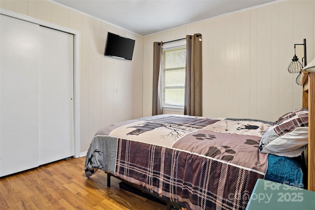 bedroom with a closet, ornamental molding, and light hardwood / wood-style flooring