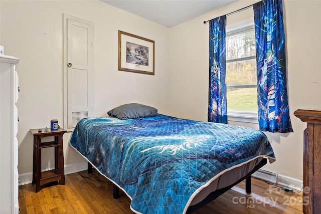 bedroom with multiple windows, wood-type flooring, and a baseboard radiator