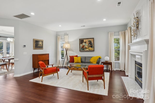 living room with a high end fireplace and dark hardwood / wood-style flooring