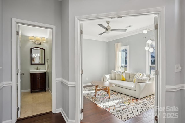 living room with dark hardwood / wood-style flooring, sink, crown molding, and ceiling fan