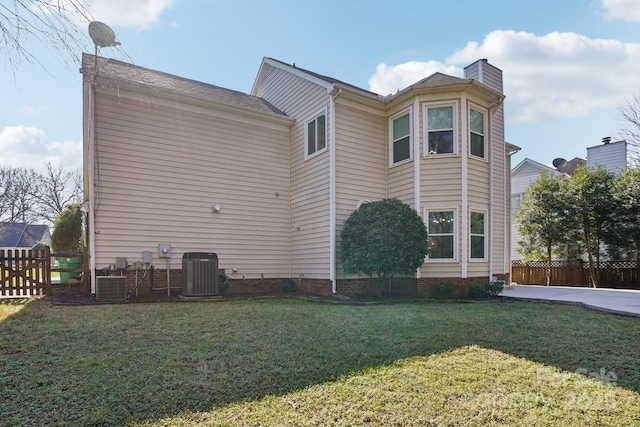 rear view of house featuring central AC unit and a lawn