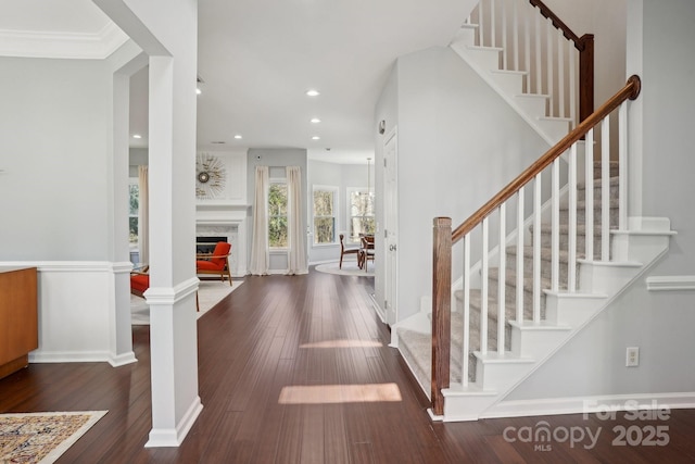 foyer featuring decorative columns, dark wood-type flooring, and a fireplace