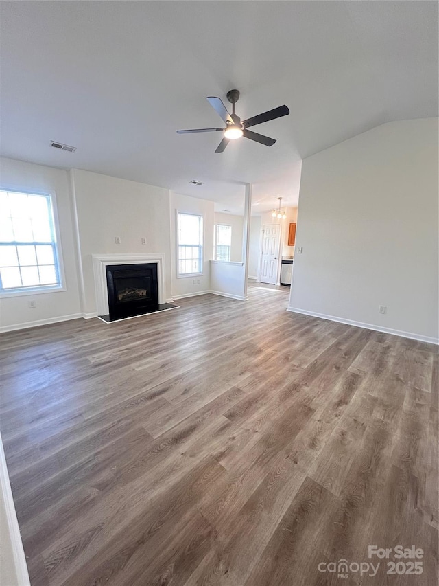 unfurnished living room with a wealth of natural light, a fireplace, visible vents, and wood finished floors