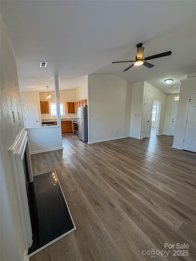 unfurnished living room featuring dark wood-style floors, lofted ceiling, visible vents, a ceiling fan, and baseboards