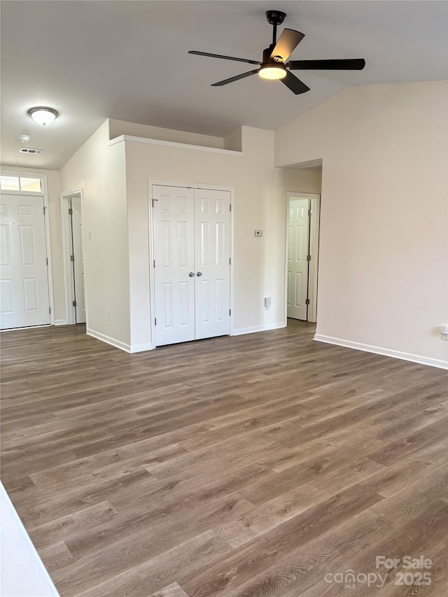 spare room with visible vents, vaulted ceiling, baseboards, and wood finished floors