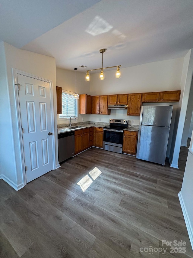 kitchen featuring brown cabinets, hanging light fixtures, stainless steel appliances, light countertops, and under cabinet range hood