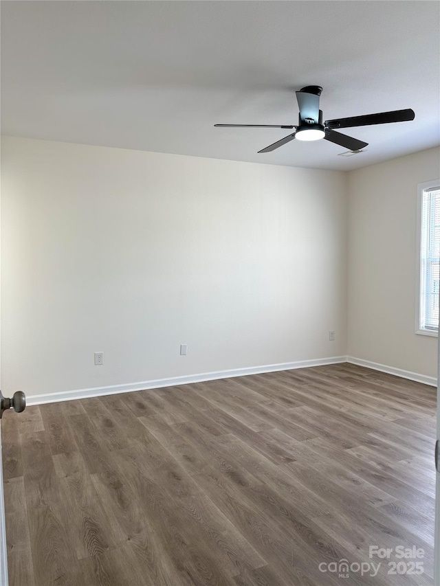 unfurnished room with a ceiling fan, baseboards, and dark wood-type flooring