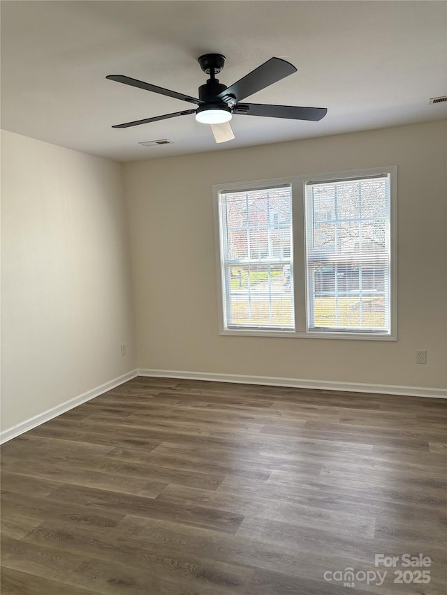 unfurnished room featuring dark wood-type flooring, visible vents, ceiling fan, and baseboards