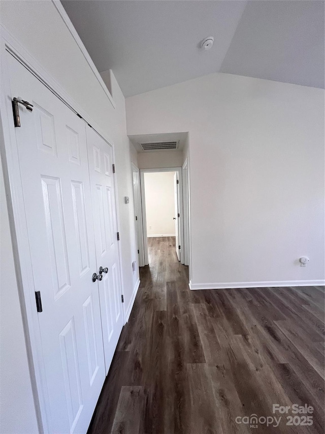 hallway with lofted ceiling, baseboards, visible vents, and dark wood finished floors