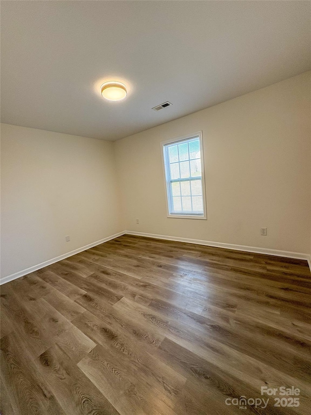 unfurnished room with wood finished floors, visible vents, and baseboards