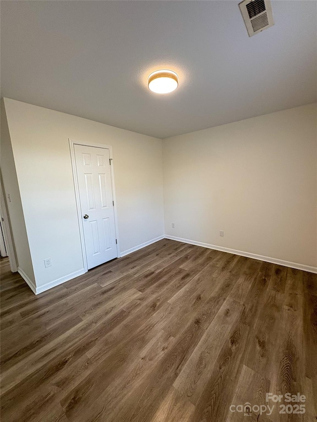 spare room featuring dark wood finished floors, visible vents, and baseboards