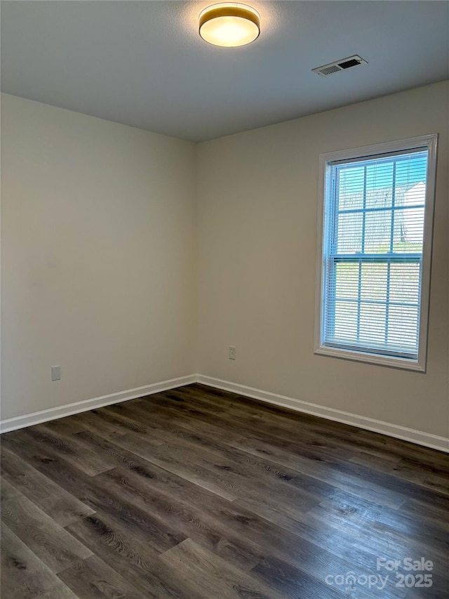 spare room with visible vents, dark wood finished floors, and baseboards