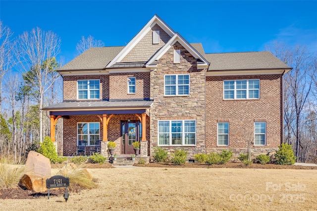 craftsman-style home featuring brick siding, covered porch, a standing seam roof, stone siding, and a front lawn