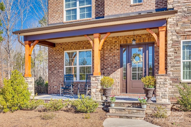 doorway to property with covered porch and brick siding