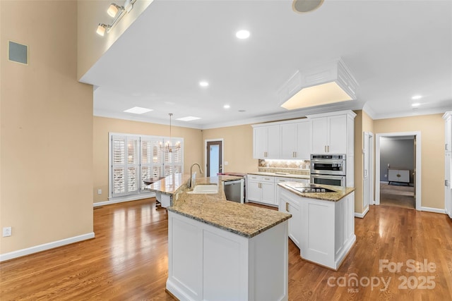 kitchen featuring sink, crown molding, an island with sink, stainless steel appliances, and white cabinets