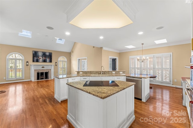 kitchen featuring pendant lighting, a center island, white cabinets, stainless steel dishwasher, and kitchen peninsula