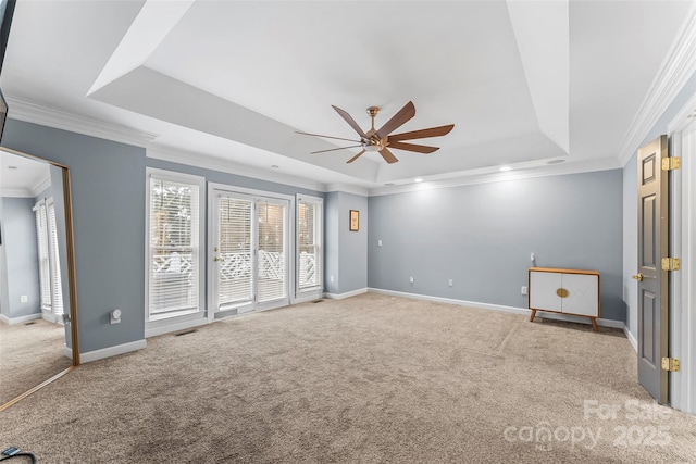 carpeted empty room featuring ornamental molding, ceiling fan, and a tray ceiling