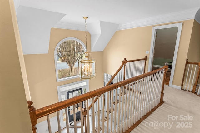 hall with an inviting chandelier, light carpet, and ornamental molding