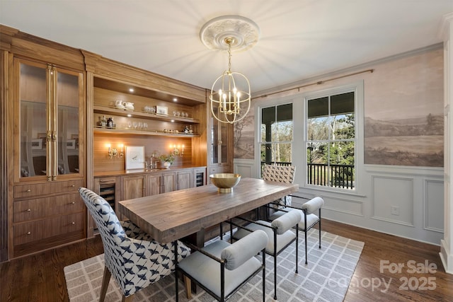 dining area with ornamental molding, dark hardwood / wood-style floors, and an inviting chandelier