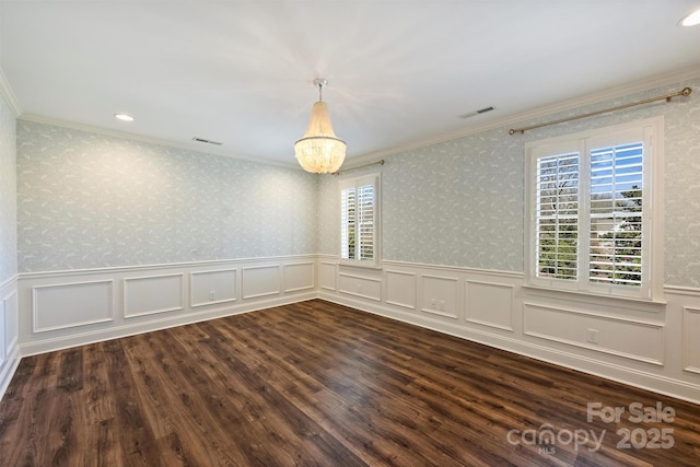 empty room with dark hardwood / wood-style flooring, ornamental molding, and an inviting chandelier