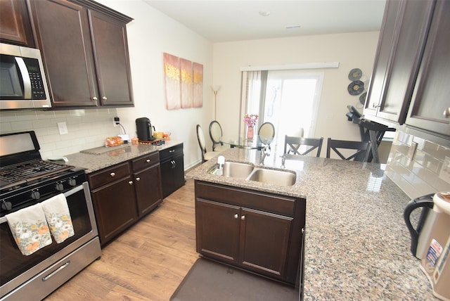 kitchen featuring light stone counters, tasteful backsplash, stainless steel appliances, and light hardwood / wood-style flooring