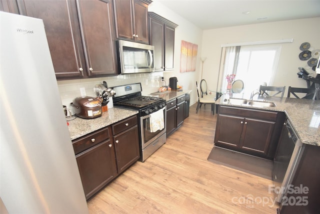 kitchen with light stone counters, stainless steel appliances, light hardwood / wood-style floors, and dark brown cabinetry